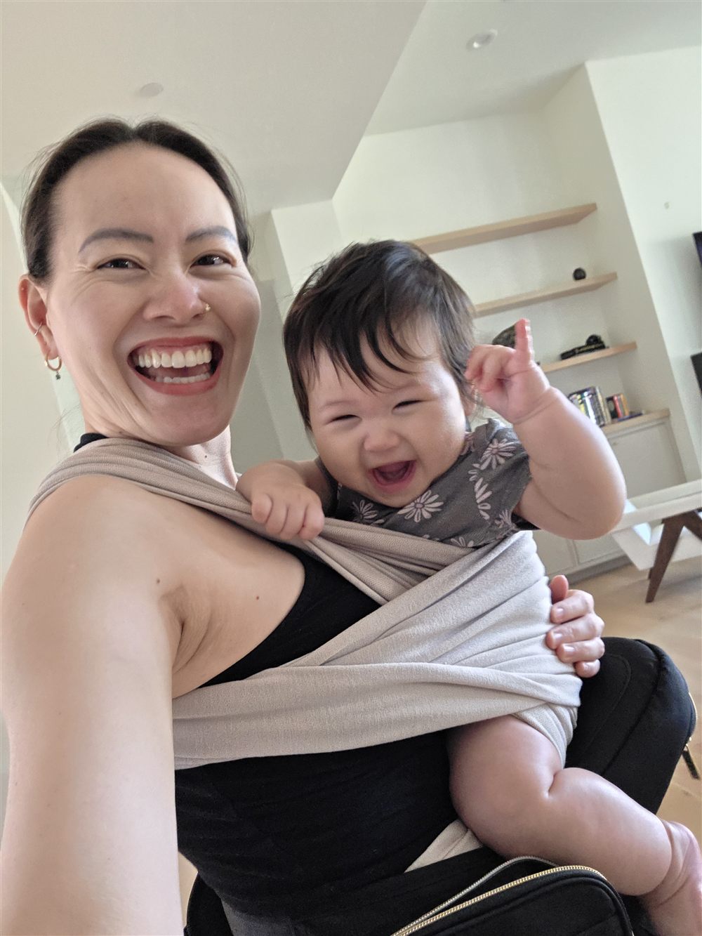 Me and my baby laughing together, her in a wrap on my chest